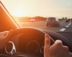 person driving car, view from the steering wheel out into traffic